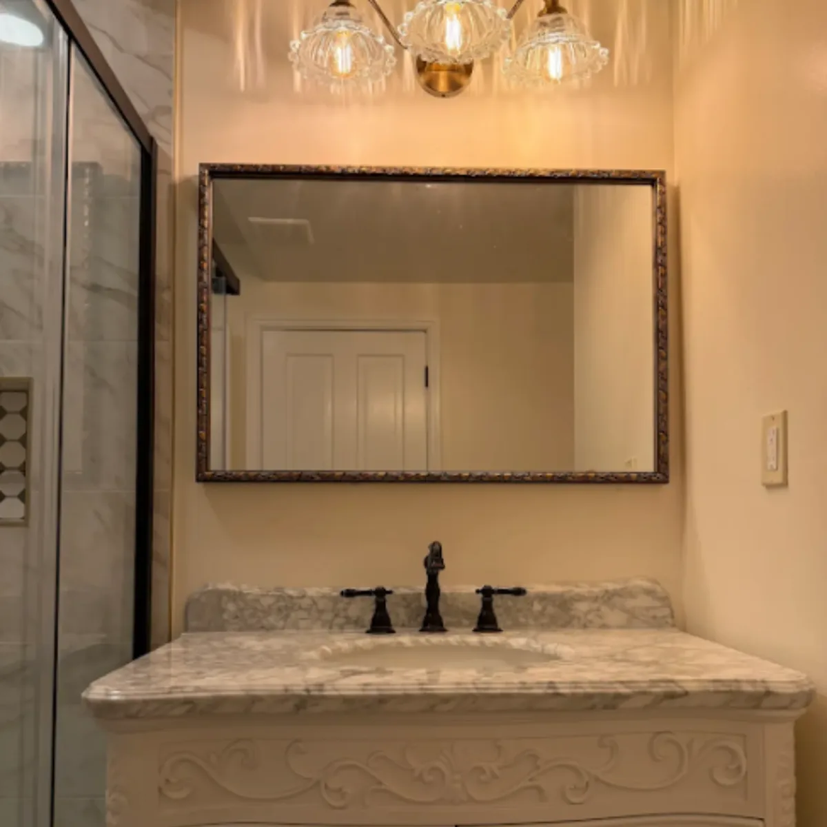 Crystal vanity light above a framed mirror and marble-top vanity in a Columbia bathroom