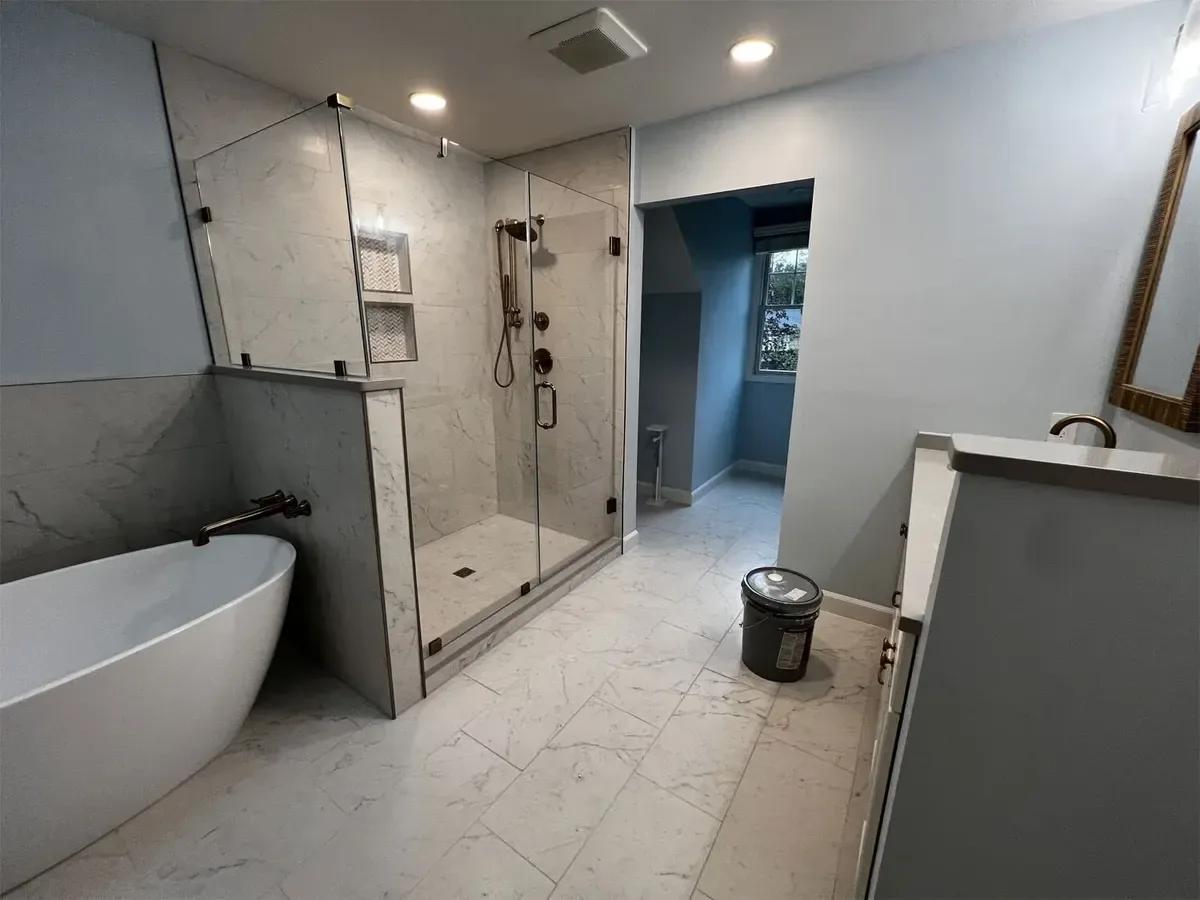 Frameless glass shower enclosure with marble-look tile in a Columbia primary bathroom