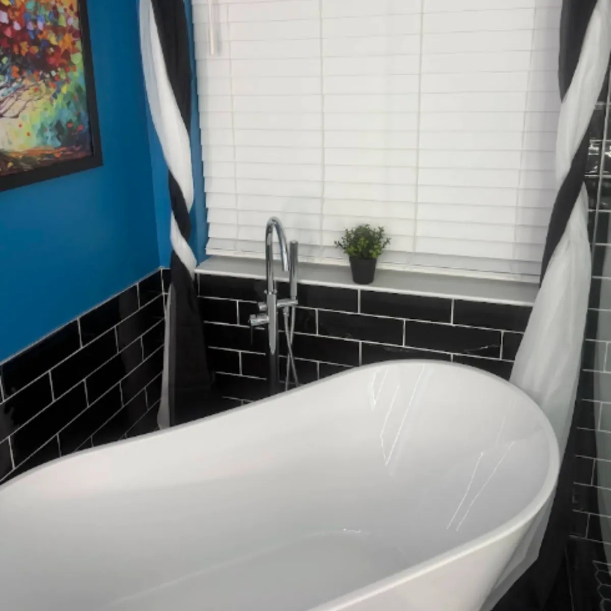 Black subway tile wall with white grout behind a freestanding slipper tub