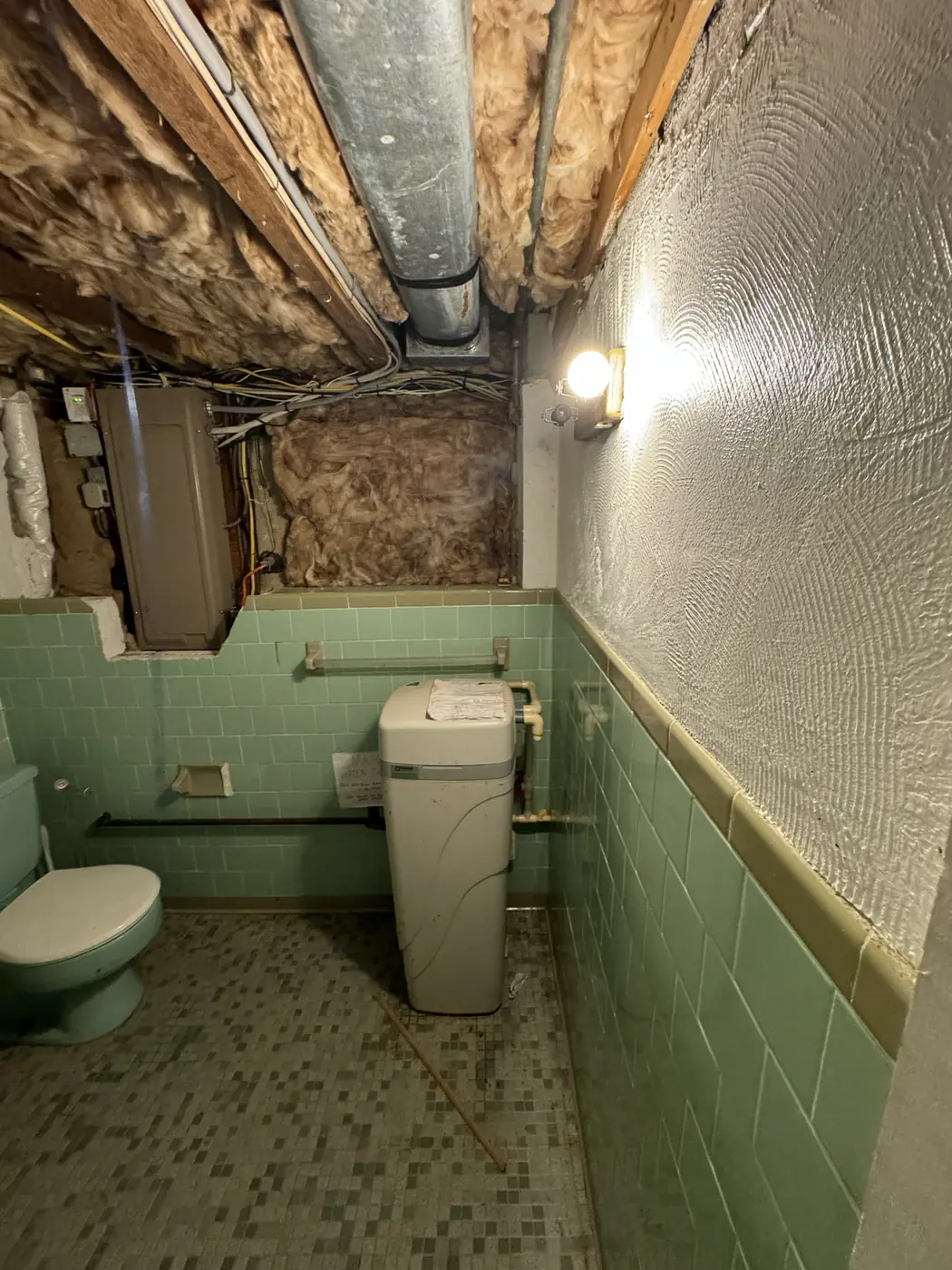 Opened walls and ceiling around an older toilet during bathroom demolition