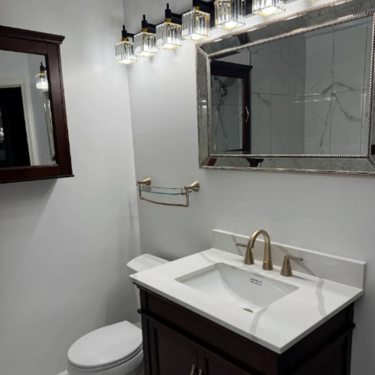 Dark wood bathroom vanity with a white top and gold faucet after installation