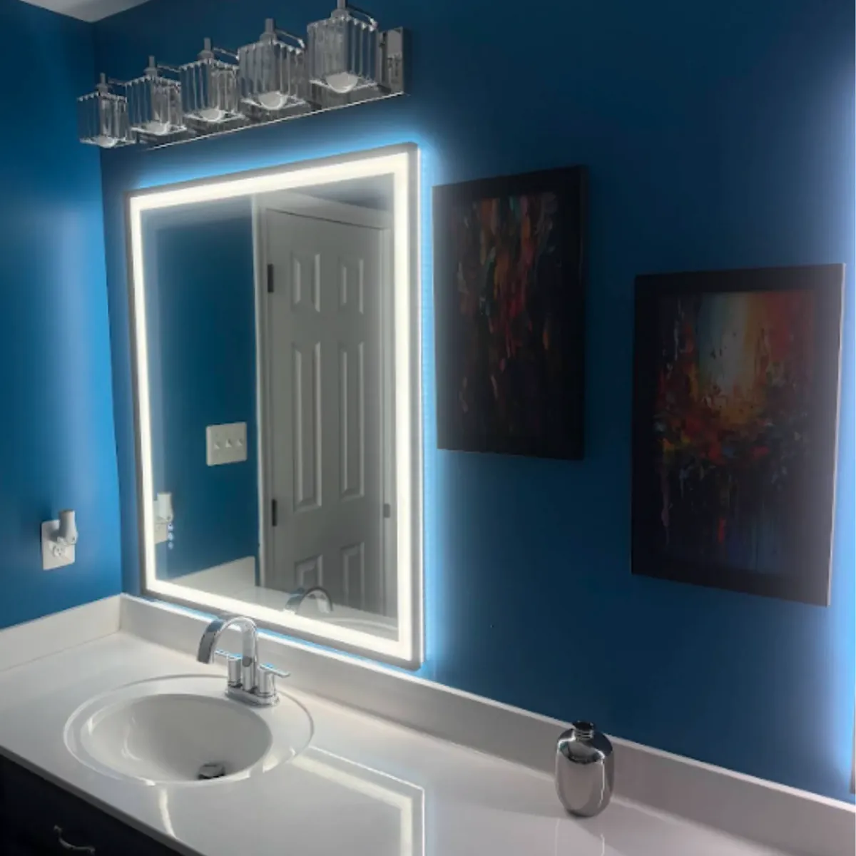 White vanity top, sink, and lighted mirror after a bathroom vanity installation