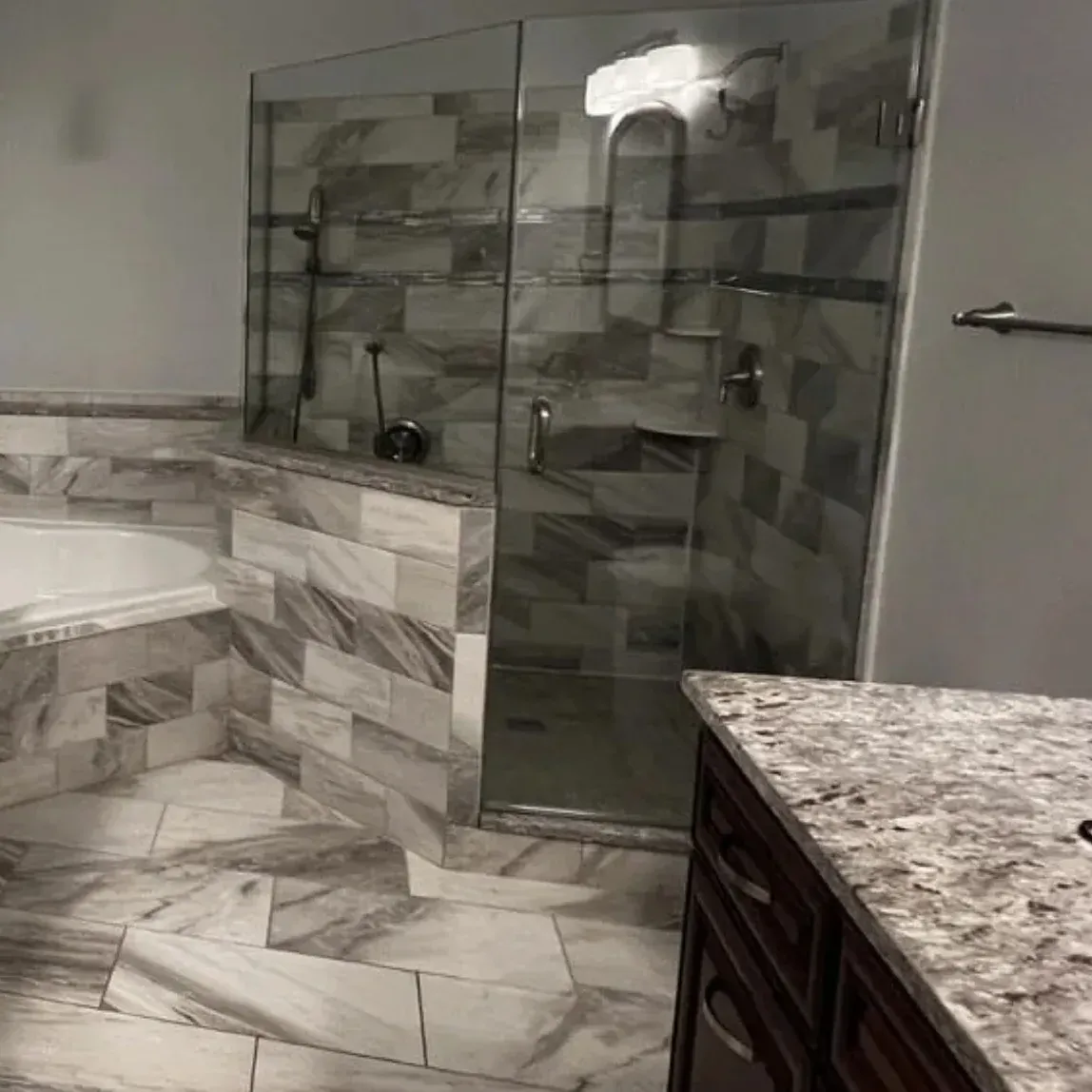 Glass shower built on a low tiled curb in an Arnold MD bathroom remodel, a step over entry not a roll in