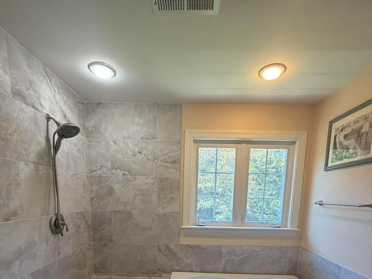Flush ceiling light and a recessed can above a tiled tub area in a Pasadena, MD bathroom