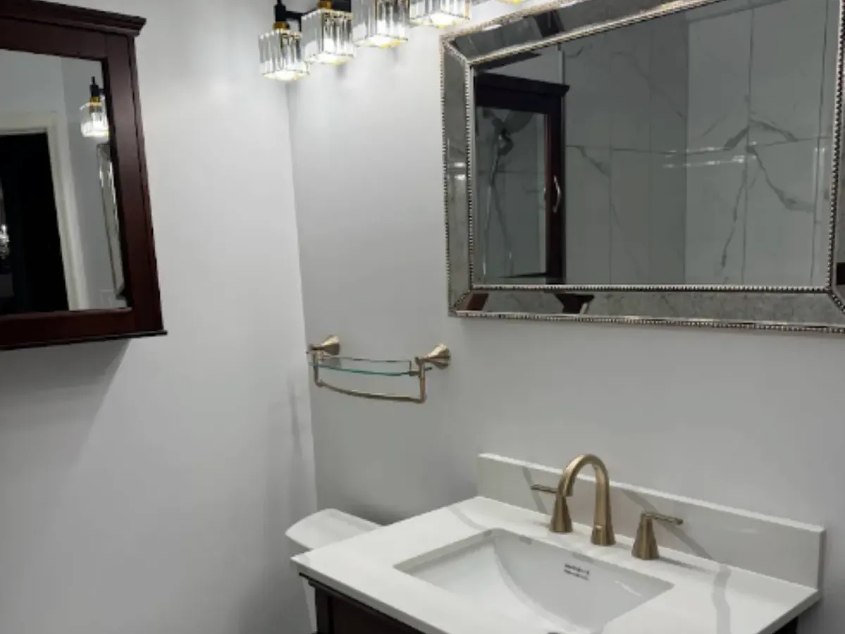 Crystal light bar above a framed mirror and white vanity in a Pasadena, MD bathroom