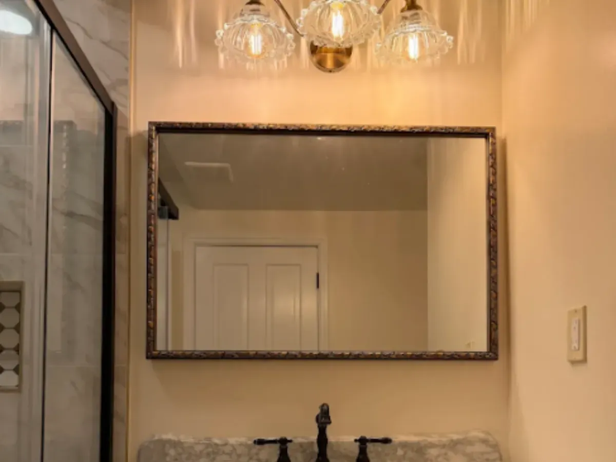 Three globe vanity lights above a framed mirror in a Pasadena, MD bathroom