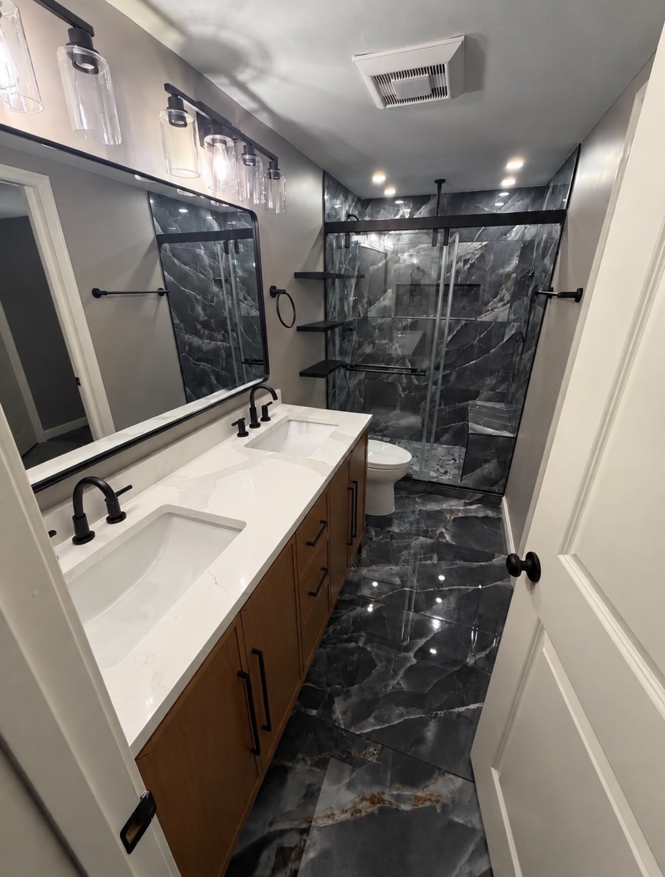 Finished bathroom remodel in Pasadena MD with black marble tile floor and double vanity