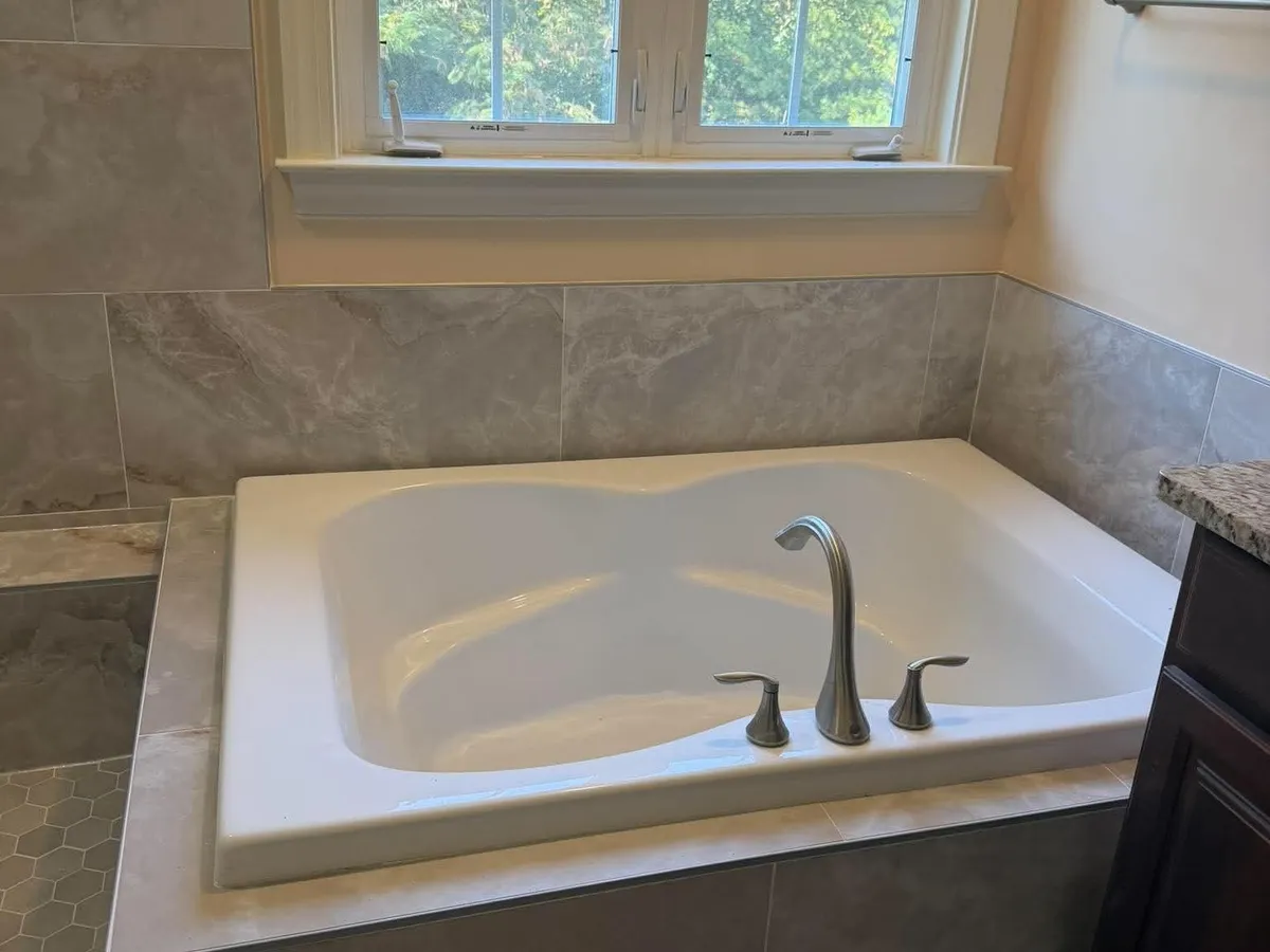 Drop-in soaking tub with a granite deck beside a window in a Pasadena MD bathroom