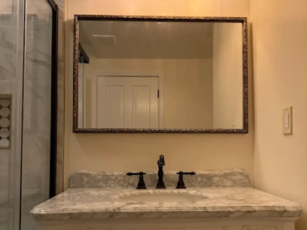 Single bathroom vanity with a marble top, framed mirror and bronze faucet in Pasadena MD