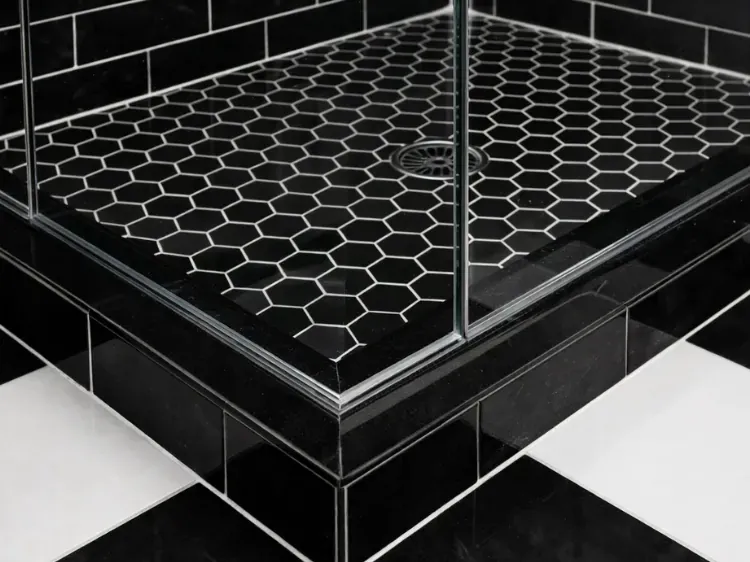 Glass shower door sealed at a black tile curb above a hex mosaic shower floor in a Pasadena, MD bathroom