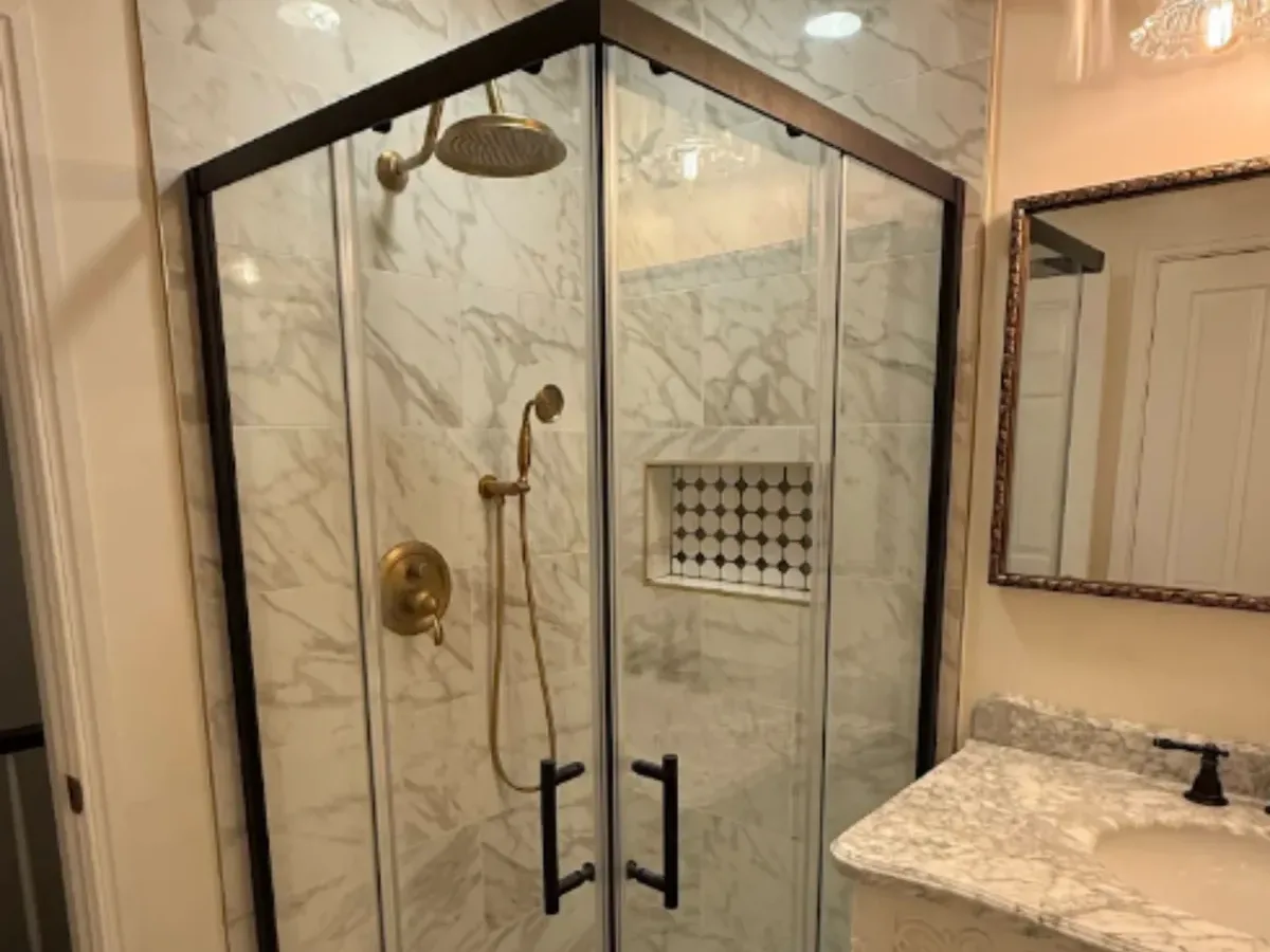 Corner glass shower with marble tile and brass fixtures in an Arnold MD bathroom remodel