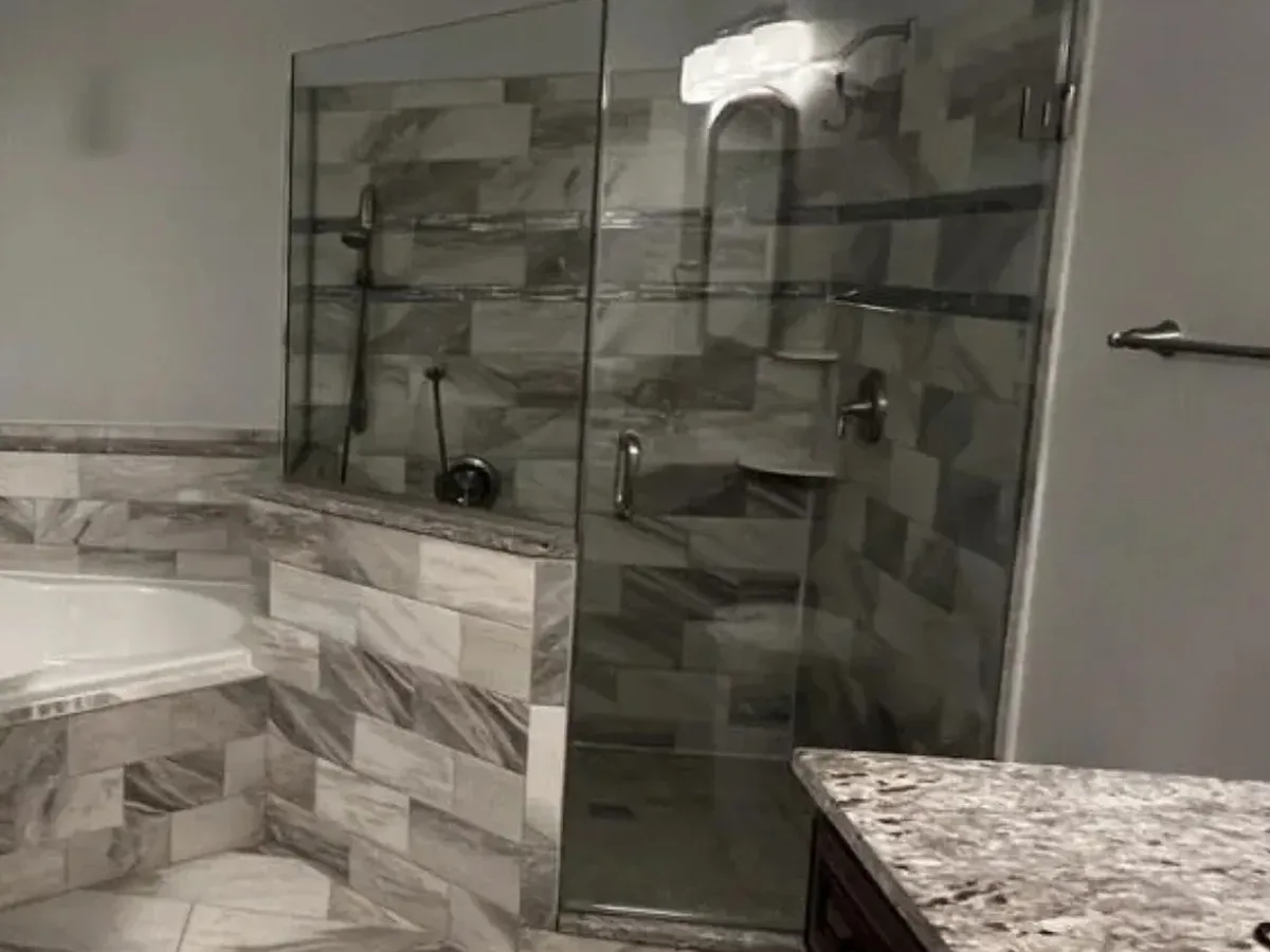 Glass shower on a tiled curb next to a corner tub in an Arnold MD primary bathroom remodel
