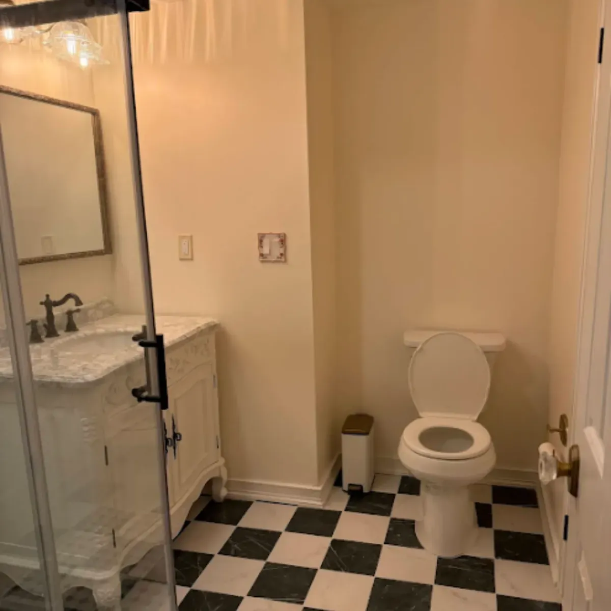 Toilet set against the finished wall in a remodeled Pasadena MD bathroom with a checkerboard tile floor