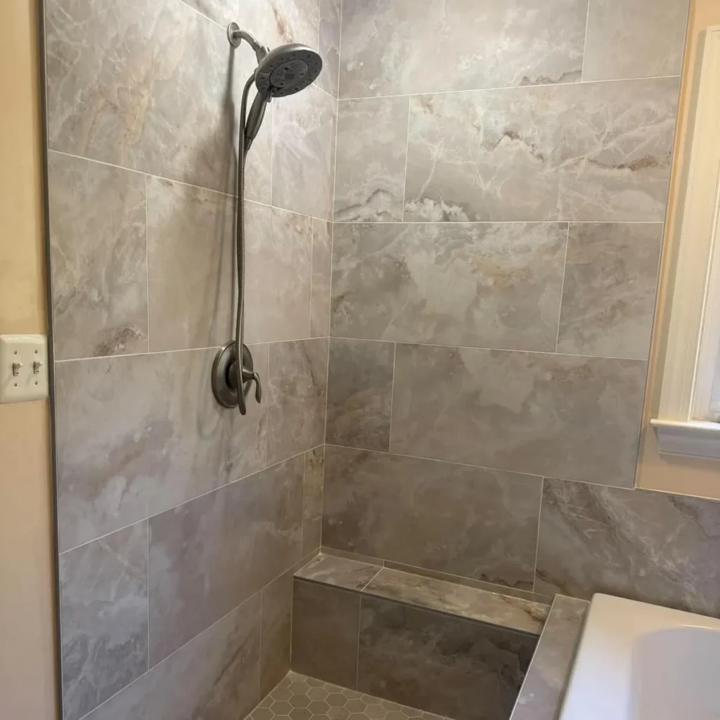 Tiled walk-in shower with a low curb and a built in bench in a remodeled Pasadena MD bathroom