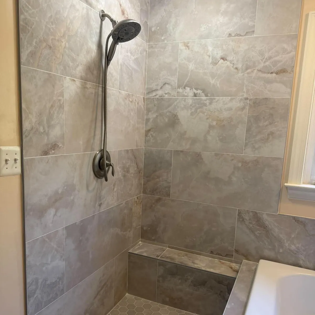 Tiled walk-in shower with a low curb and a built in bench in a remodeled Pasadena MD bathroom